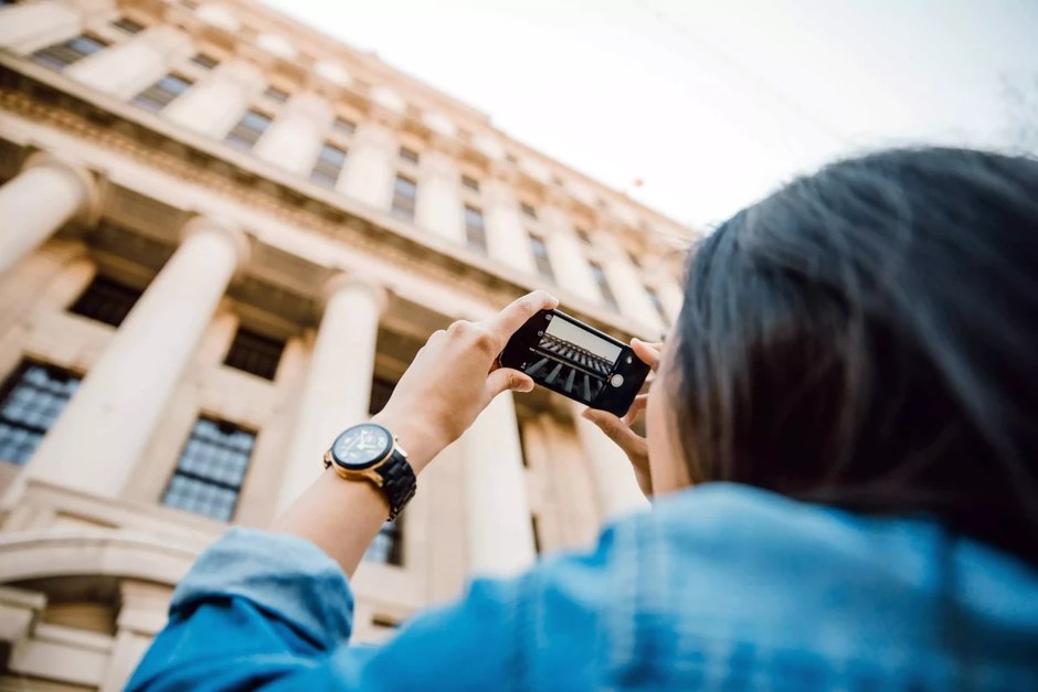 A traveler photographing architecture while exploring a city street.