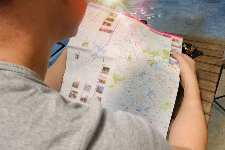 A traveler studying a paper city map during a walk.