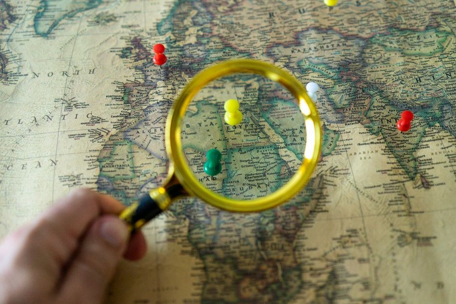 A paper map viewed through a magnifying glass, suggesting curious local exploration.