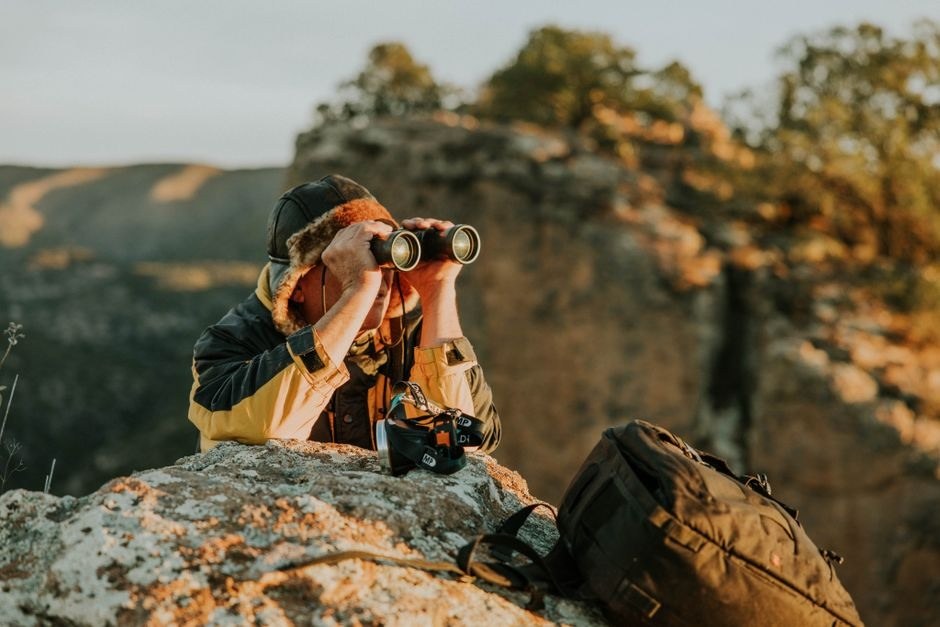 A photographer with a camera on a rocky overlook.